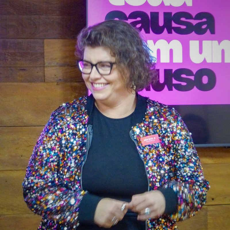 Convidada sorrindo diante do painel do Causos & Causas em São Paulo